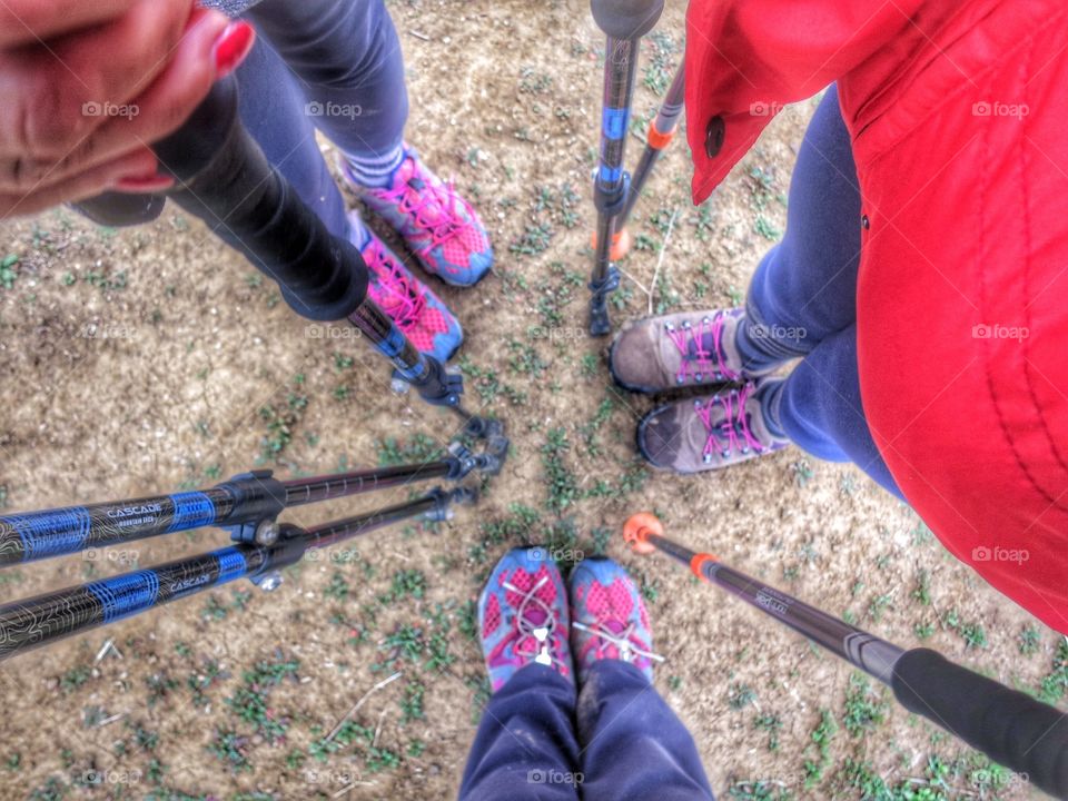 Friends looking down at their hiking boots/shoes and poles from above. 