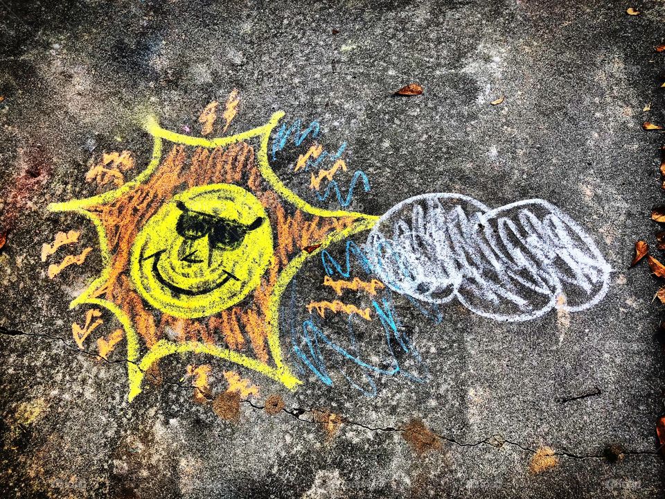 Sidewalk chalk drawing of a sun and a cloud 