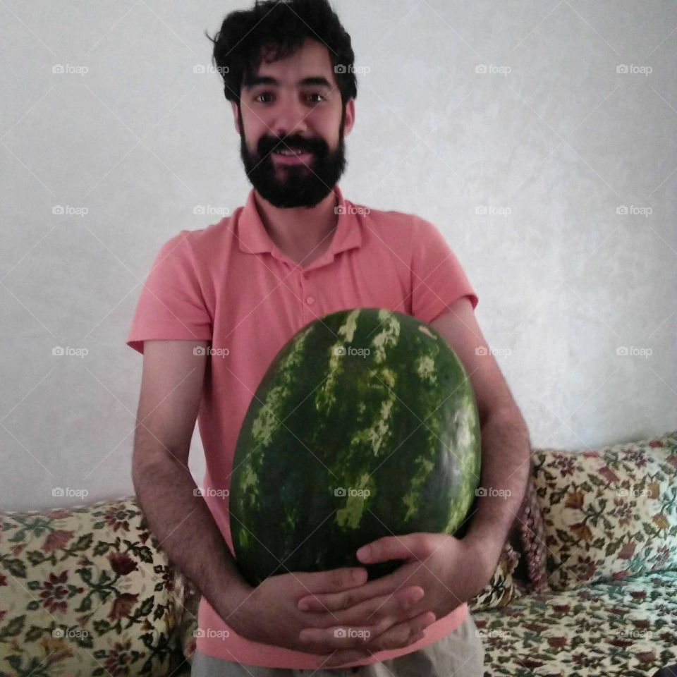 My eldest son has a green watermelon in his hand.