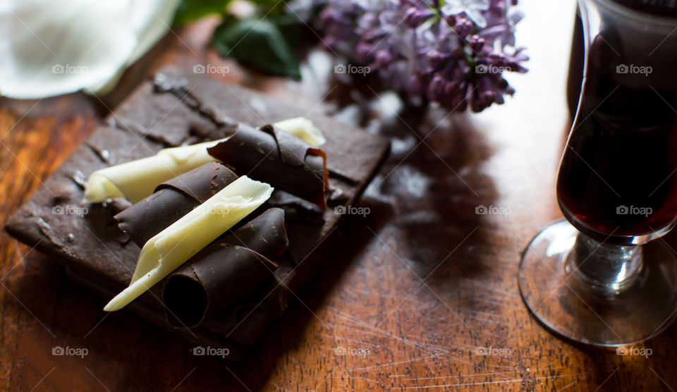 Dark chocolate with lilacs and Porto wine on dark wood table conceptual healthy eating antioxidant rich gourmet food and drink epicure background 