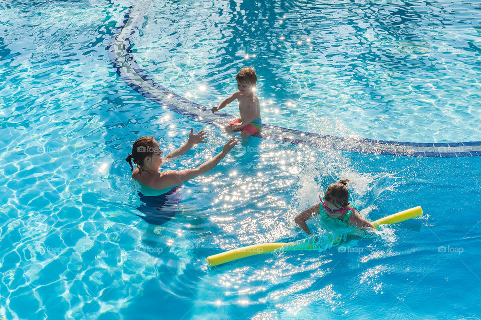 Family sport activities in swimming pool. Learning how to swim.