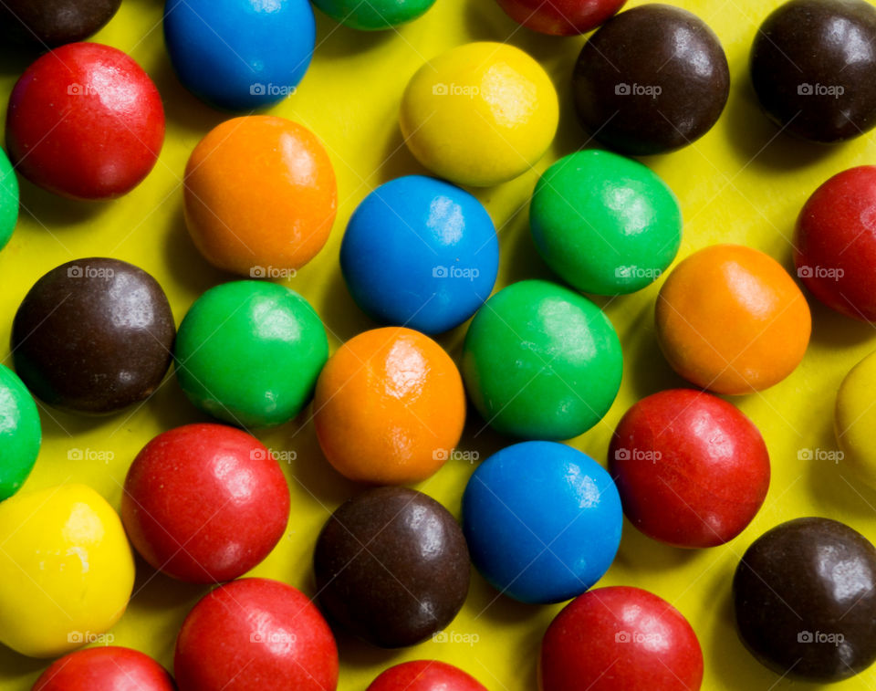 bright multicolored candies on a yellow background