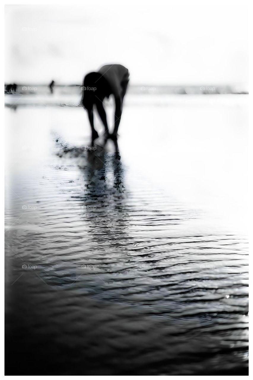 reflection of an asian girl in sea water on a beach