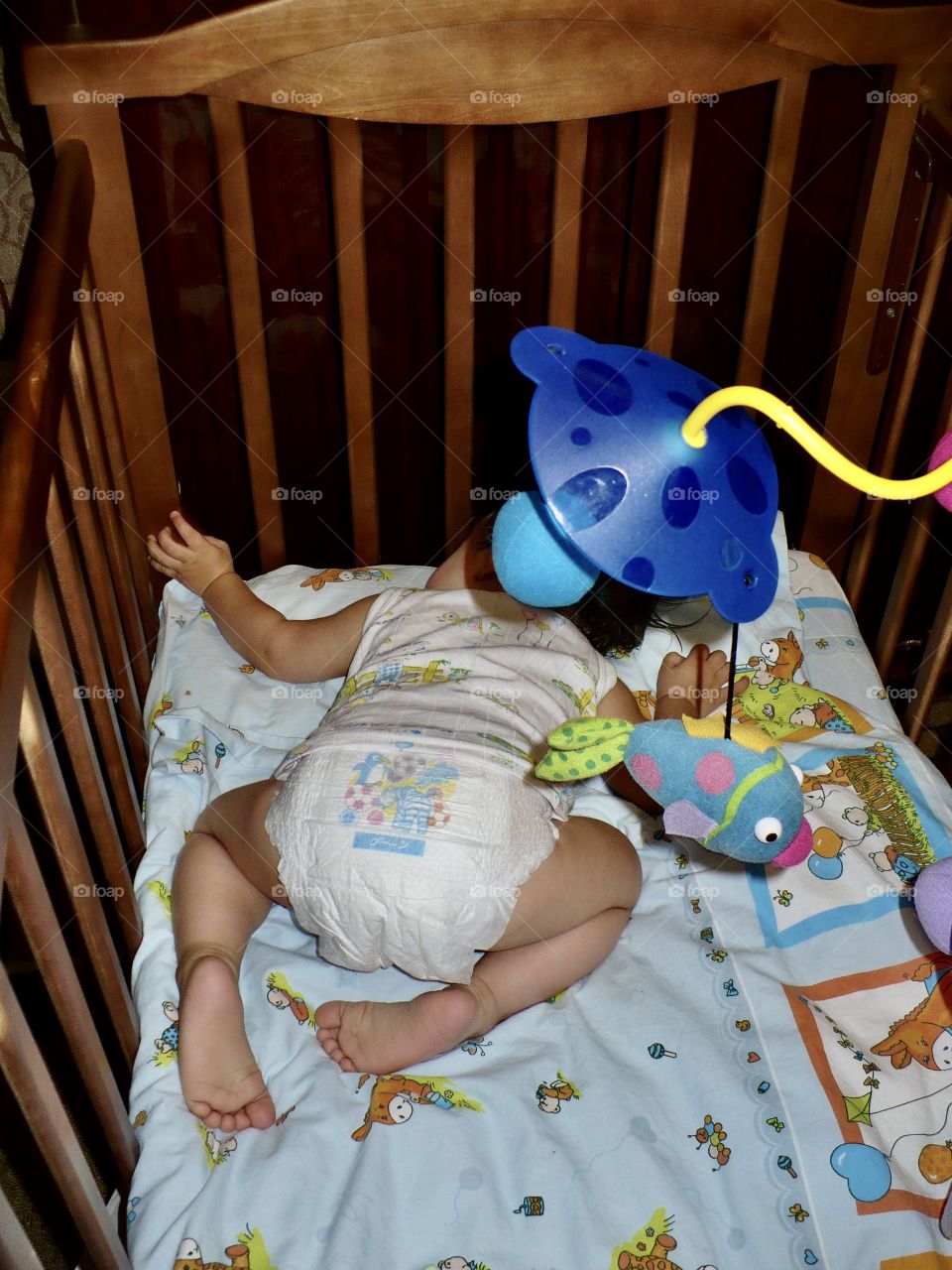 Little baby sleeps in his crib while lying on his tummy