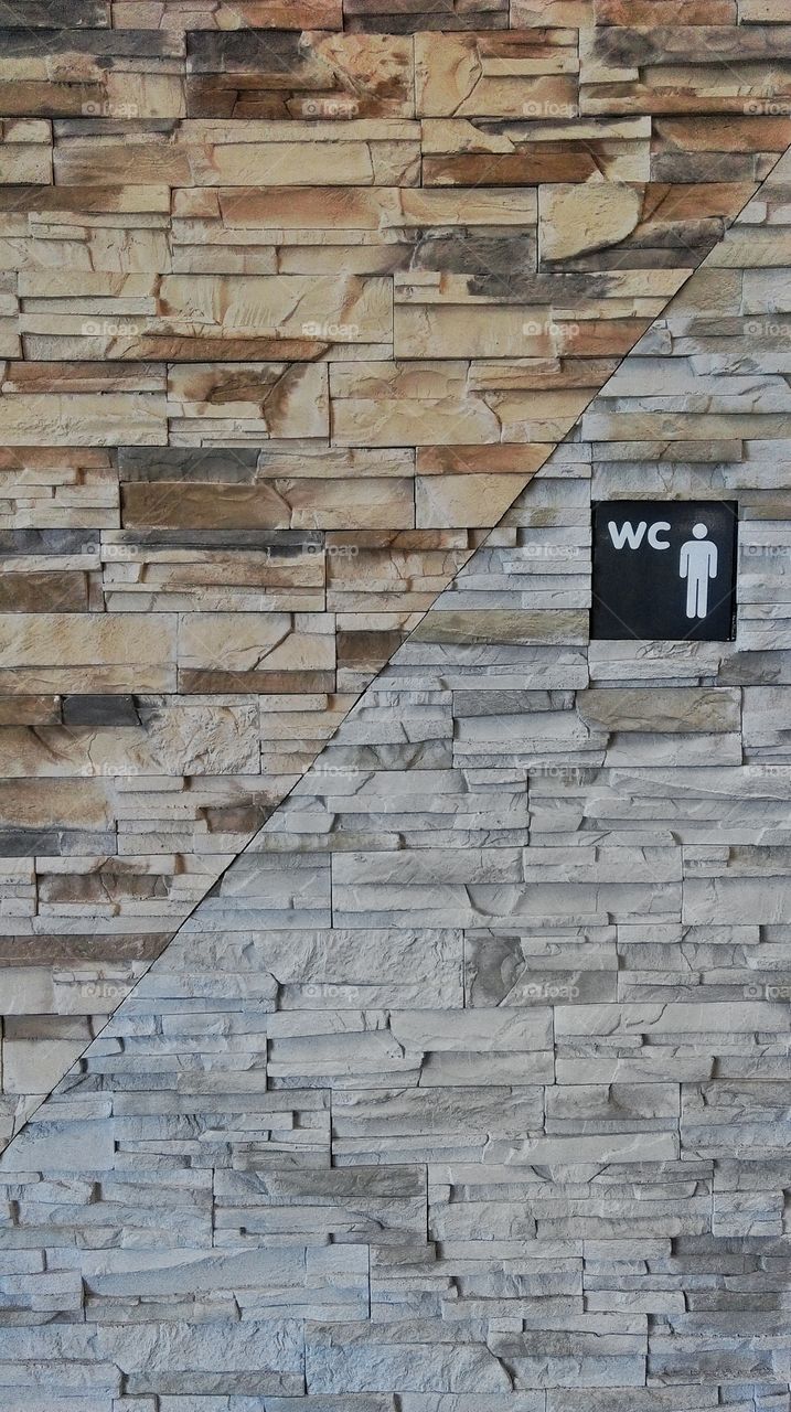 Toilet sign on stone wall