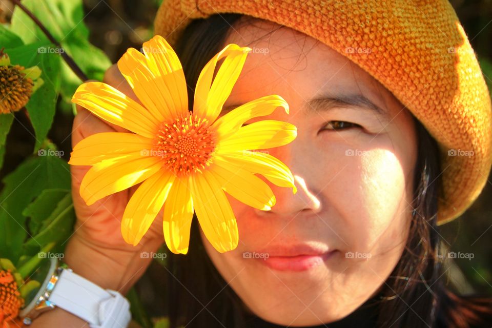 Photos of lovely women with beautiful yellow flowers blooming seasonally.  The eyes from a lovely woman and the other eye from a blooming yellow flower.