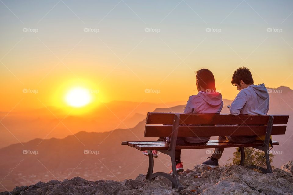 Couple watching sunset from the top of a mountain