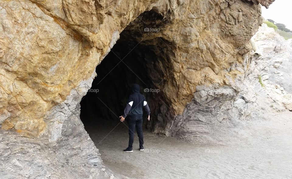 Modern day caveman. Man posing at the mouth of a cave