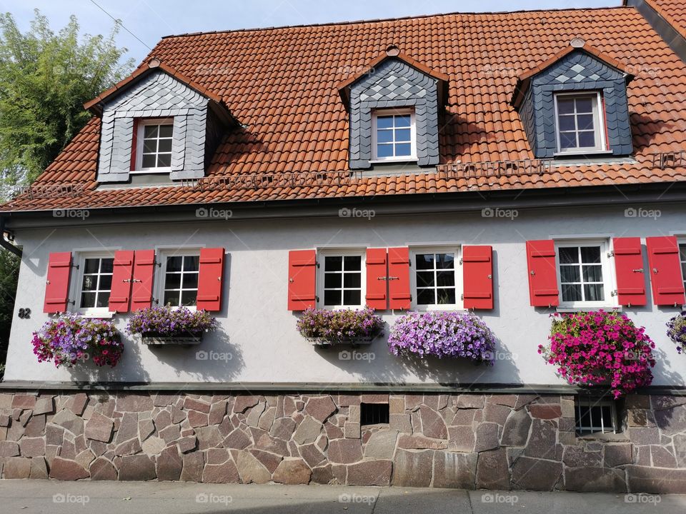 Altes Haus mit Fensterläden und Blumenschmuck