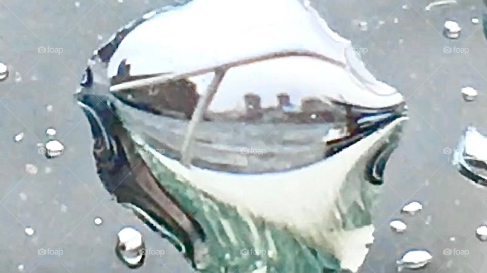 The Newtown Creek, LIC, Queens “harbor area” reflects in a single large drop of water on the front deck of “Salvation”, our boat incl. the metal railing, the fiberglass deck and Greenpoint, Bklyn across the E River. 2021. Hypnotic Productions