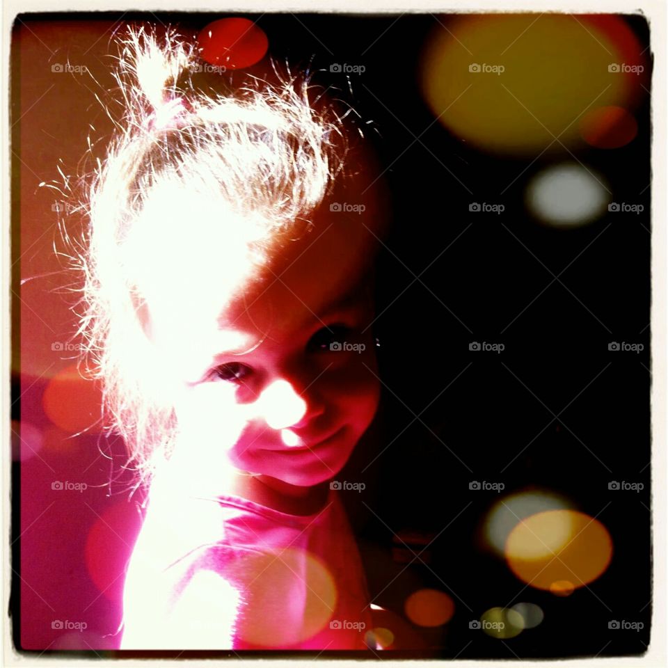 The morning sun strikes the face of a smiling little girl