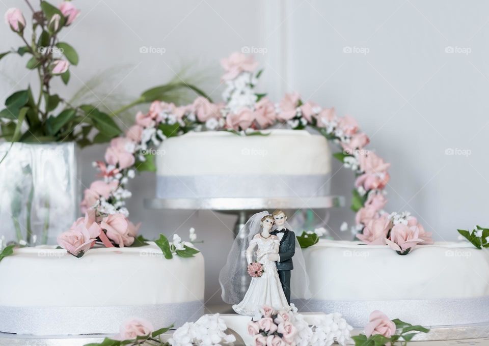 A white wedding cake decorated in pink icing flowers 