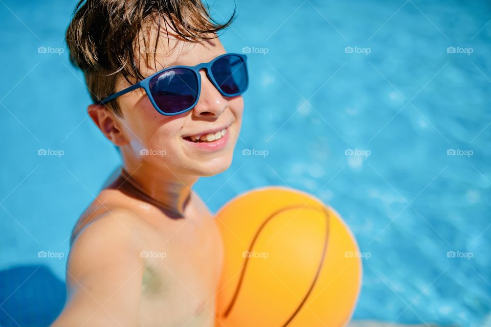 boy makes funny selfie in the pool