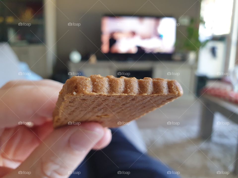 A point of view portrait of somoene eating a sweet spiced bisquit. its called speculaas in belgium.