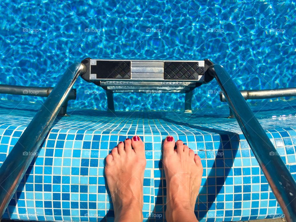 Low section of person standing near swimming pool