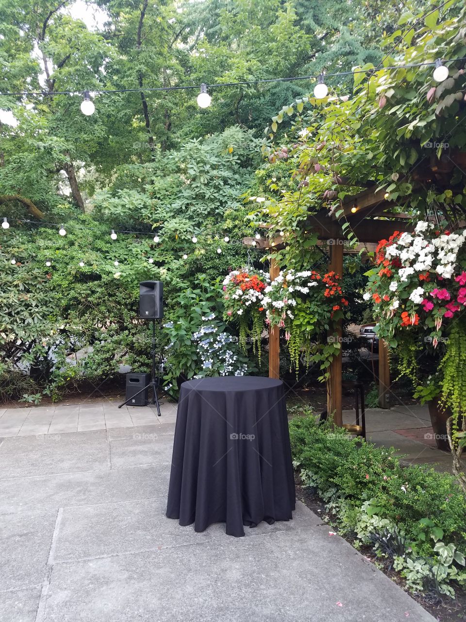 Cocktail table at an outdoor garden summer wedding with string lights and flowers on a patio