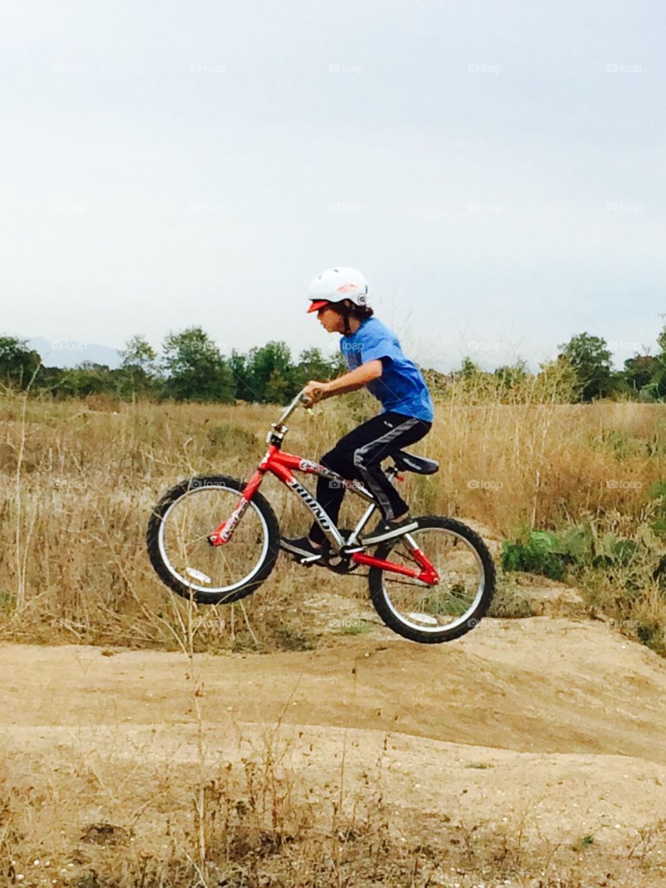 Boy going for a little air. My son likes to ride the jumps in the nature preserve behind our house. 