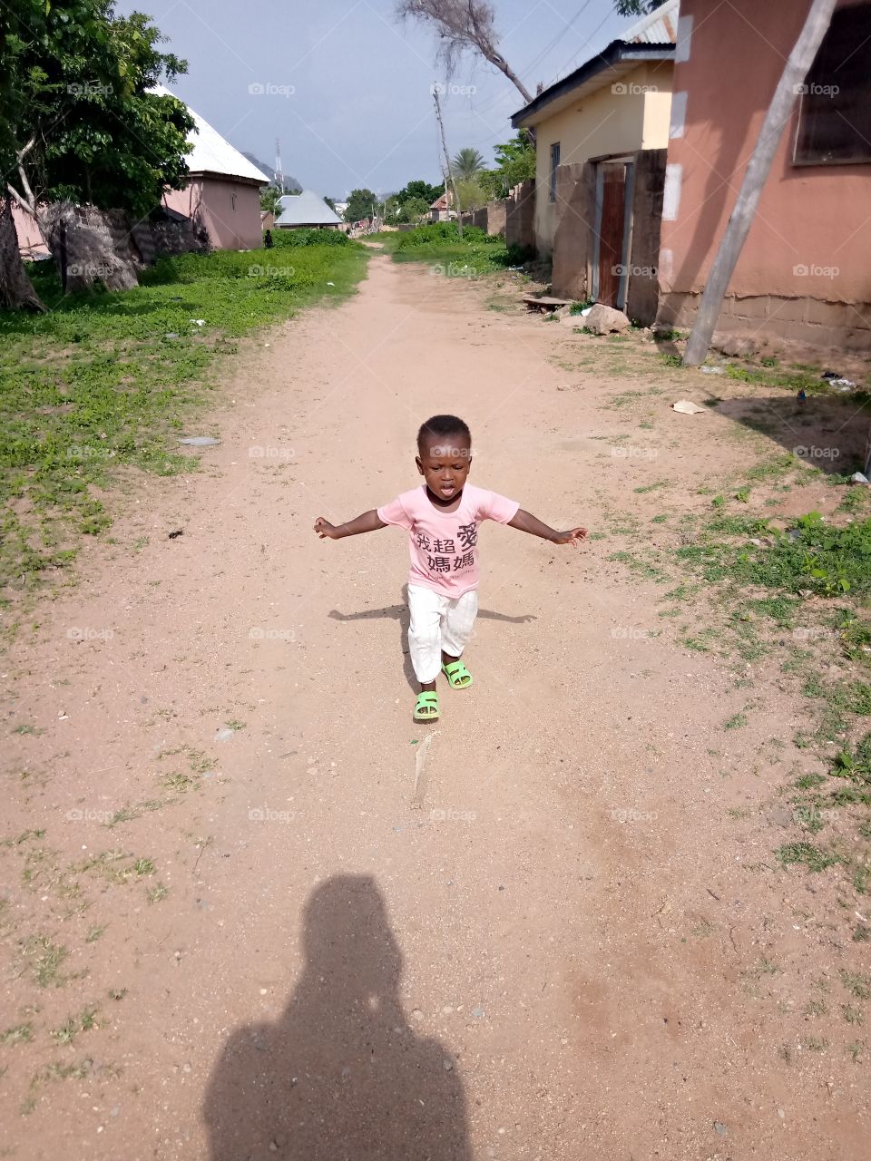 a child running to welcome his mother, in mission ward of Zing local government of Taraba state Nigeria. life is sweet with kids around us. it's just a street photo without editing.