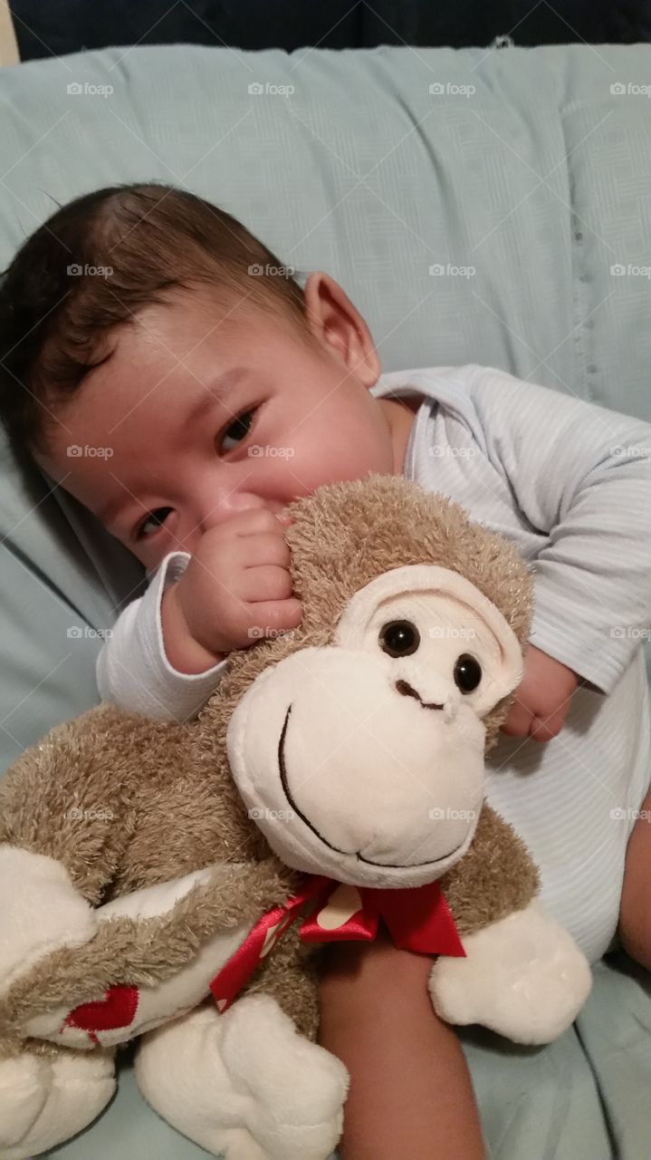 baby cuddles with monkey