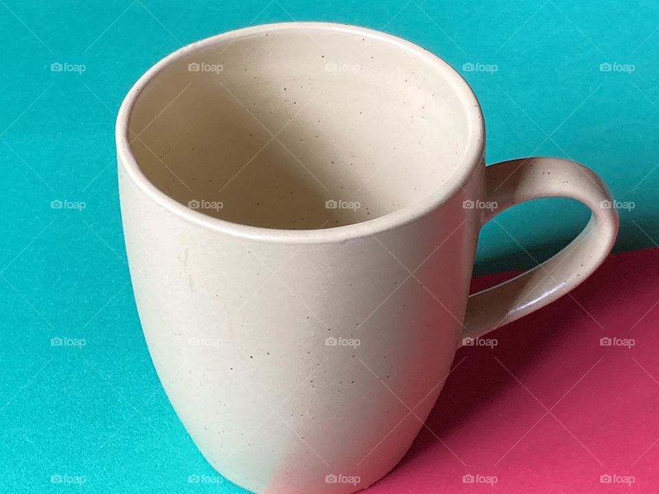 Caneca verde claro em fundo verde com outra tonalidade, no canto um vermelho.