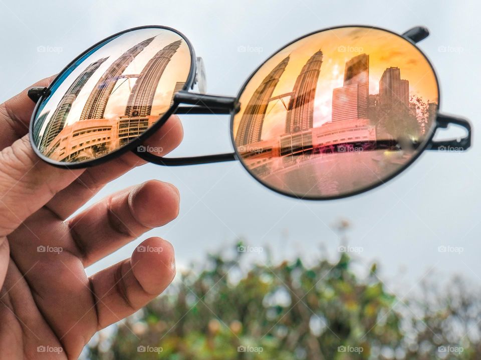 Reflection of the Petronas towers on the circular sunglasses