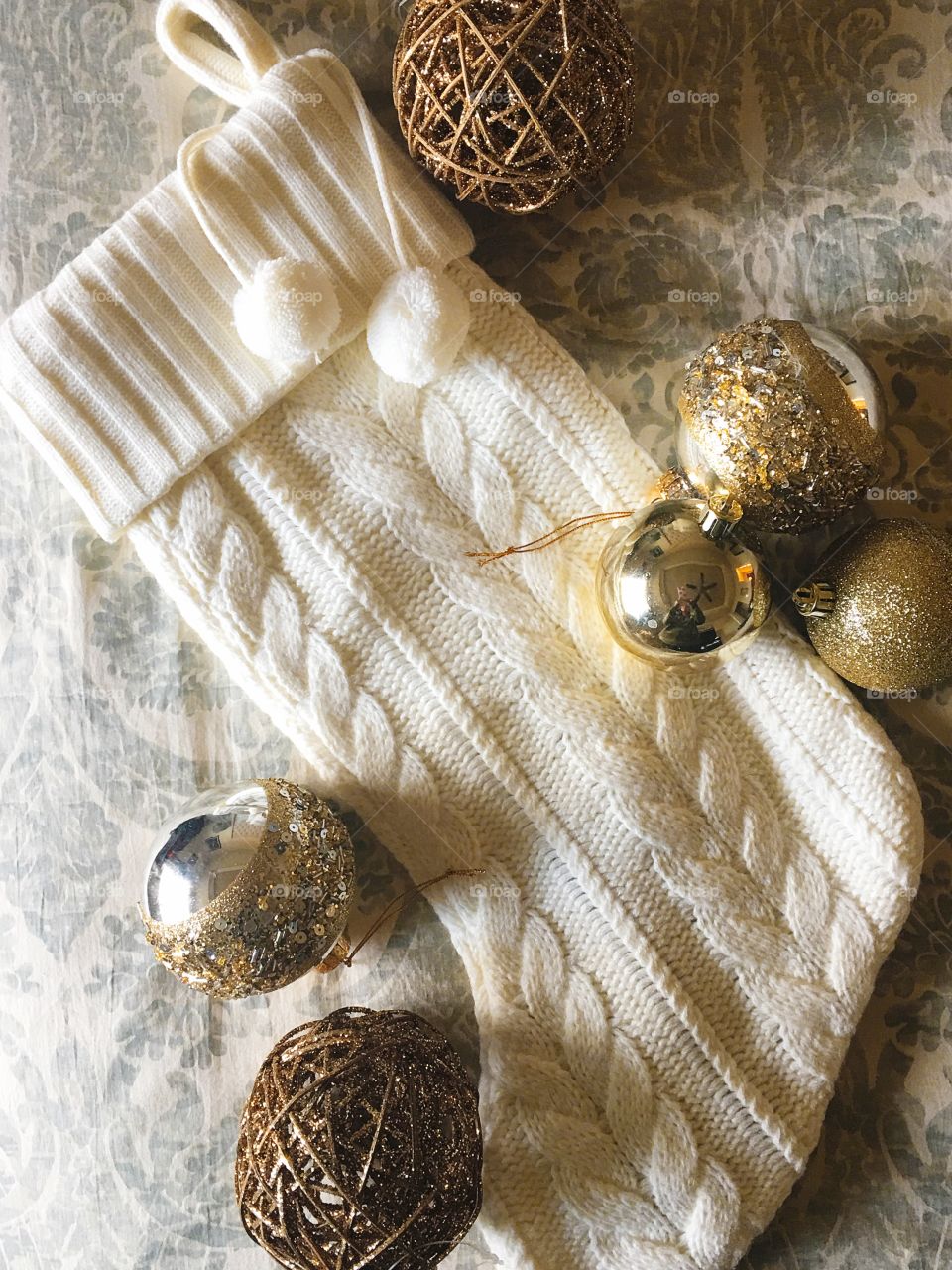 Holiday knit stocking with gold ornaments.