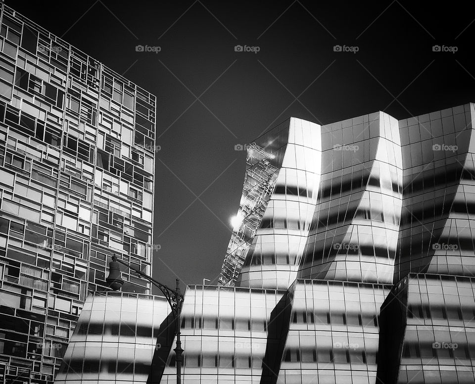 Two modern buildings on Manhattan’s west side, with one reflected on the mirrored surface of the other