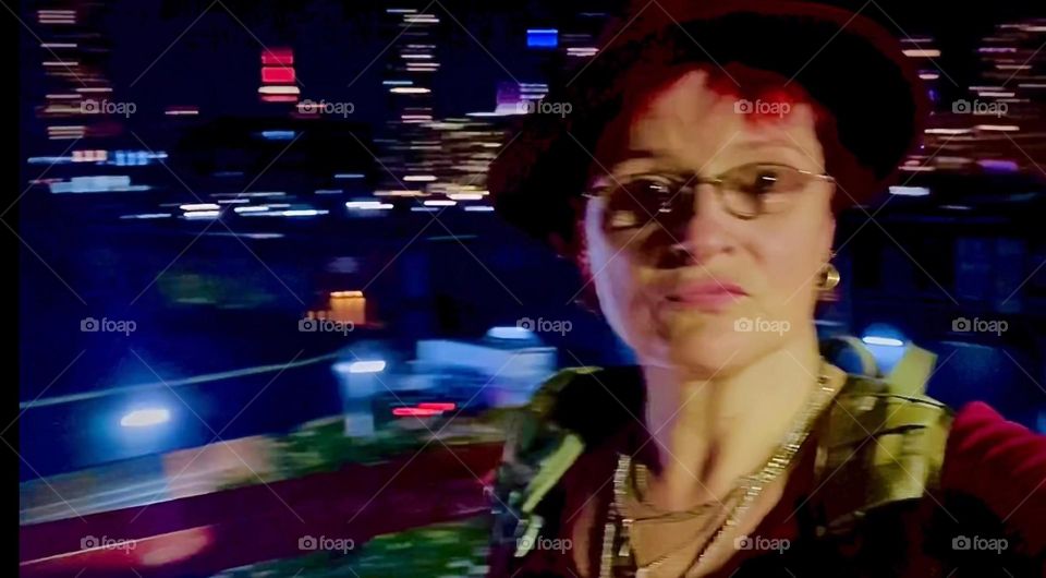 An interesting play of lights, colors and patterns is achieved in this photograph of myself, “Petra Schiller” a.k.a. “Maxine Firefox” ascending the red metal staircase of the “Pulaski Bridge” at “Newtown Creek”. 2022. Hypnotic Productions