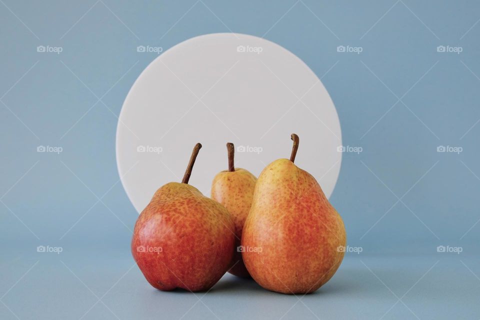 Still life with three orange pears against blue background. 