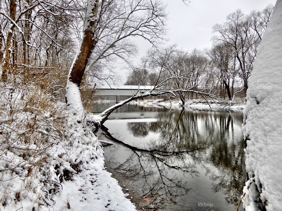 A winter day on the white river in Indiana with the old covered bridge with snow on the ground 