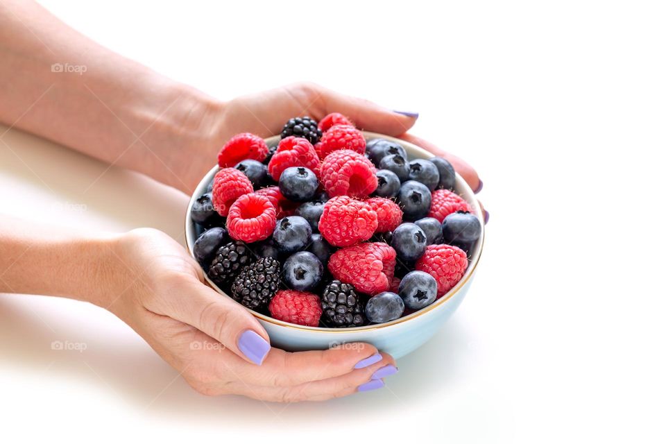 Fresh berries in a bowl, delicious healthy breakfast option in female hands