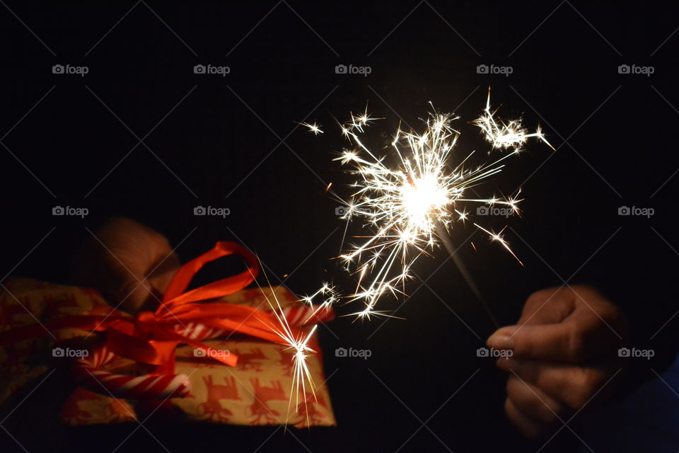 Christmas gift and bengal light in the hands dark background winter holiday