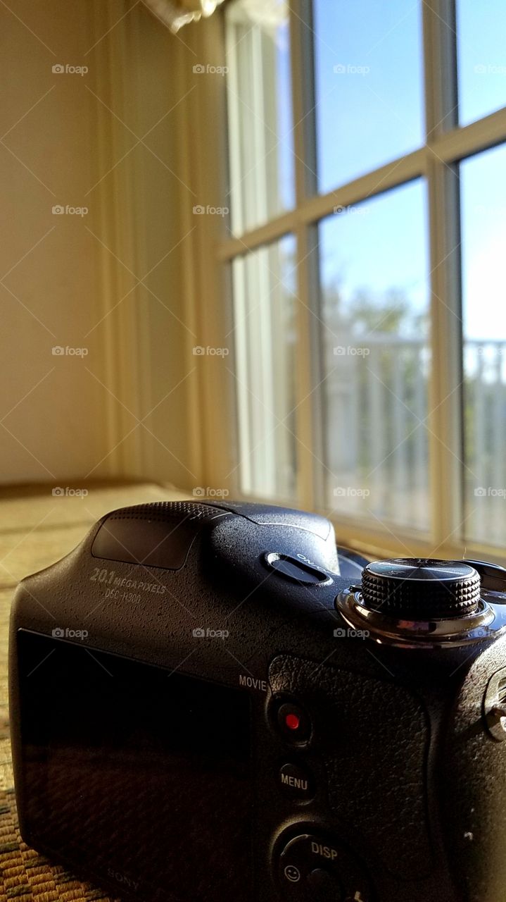 A camera on a window seat with the morning sun shining in.