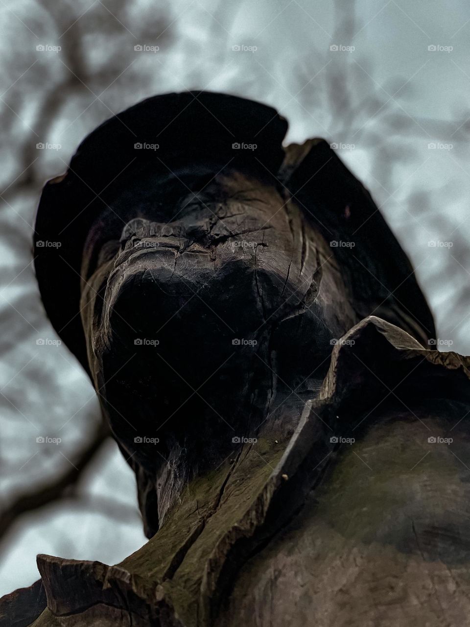 Wooden man carving aged in moss trees in background