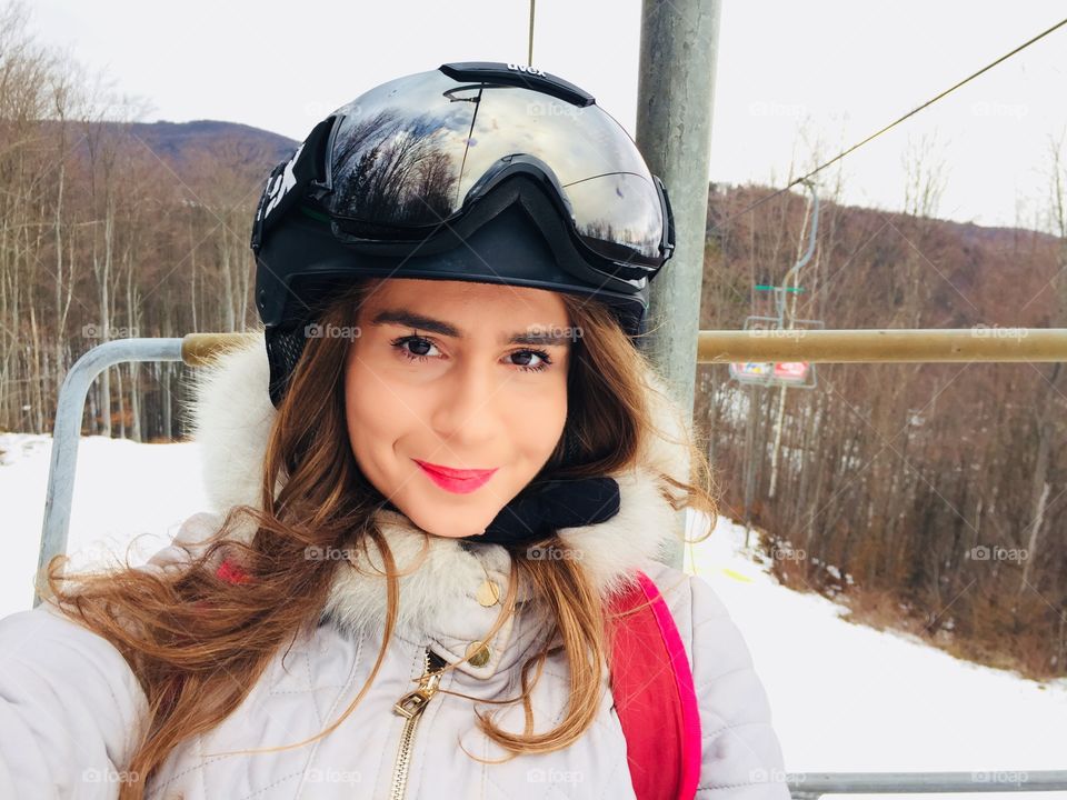 Portrait of young woman wearing Uvex ski glasses and Uvex helmet on the ski lift