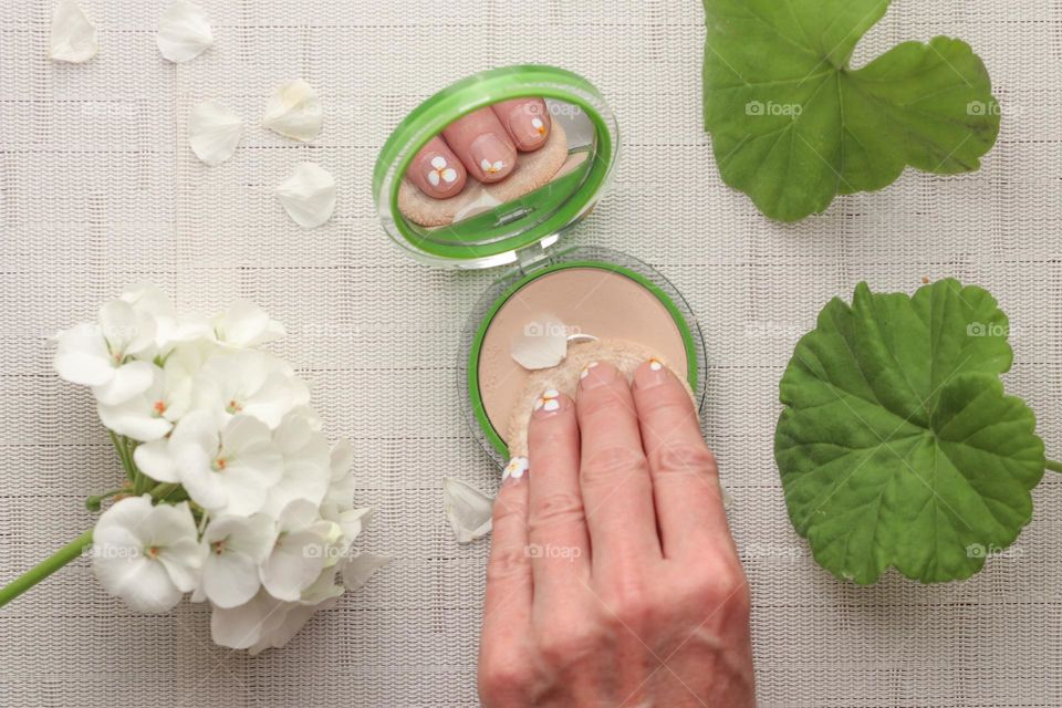 Woman's hand is holding a puff using make-up powder