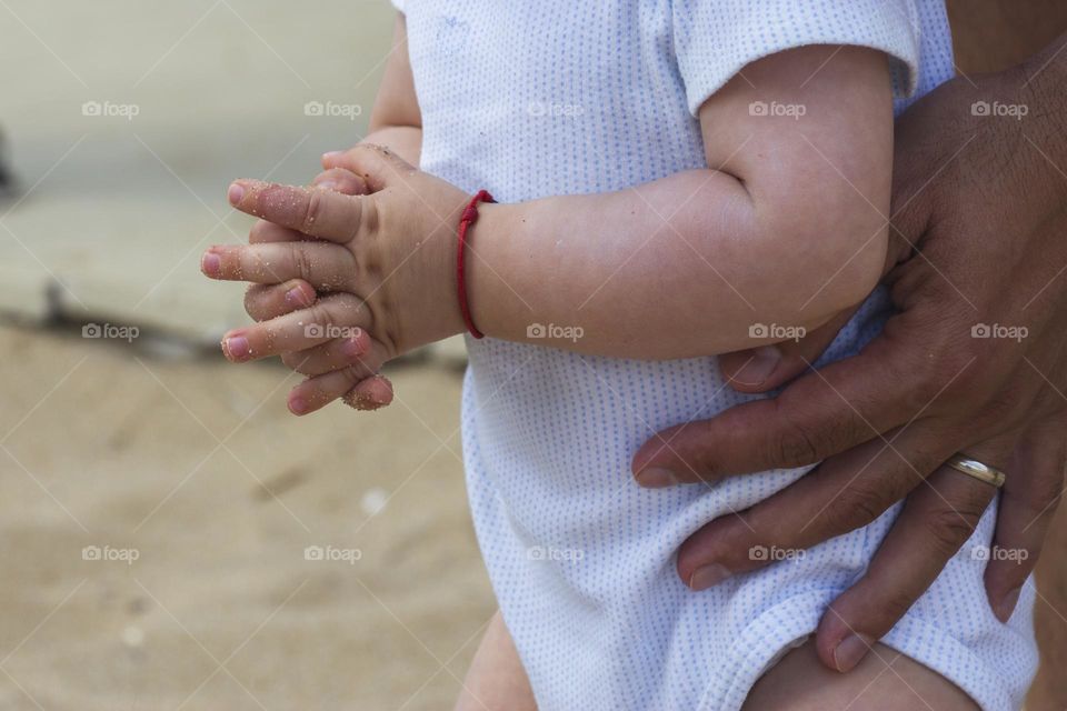 Fathers hands hold a baby son
