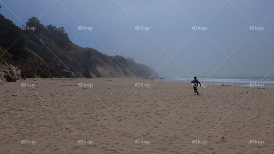 Boy running on a foggy beach