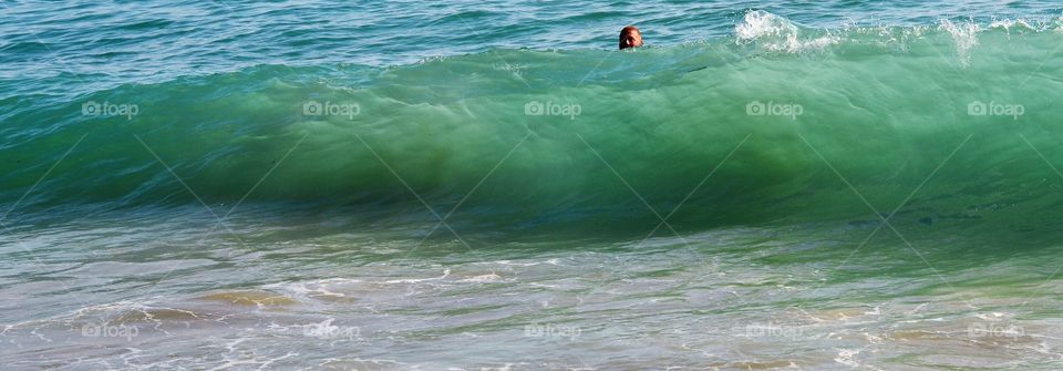 A man swimming in the sea with wave