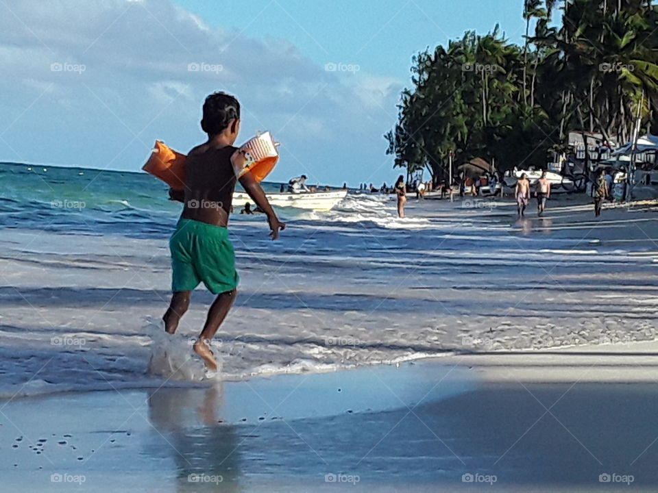 boy in inflatable swim sleeves runs on the beach