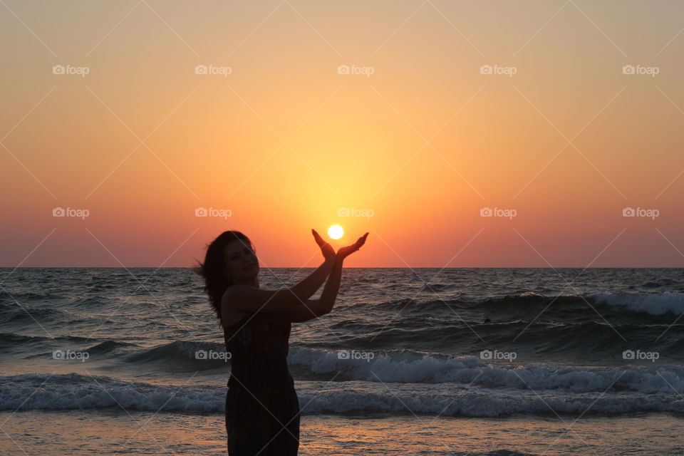 Silhouette of a woman gesturing at beach during sunset