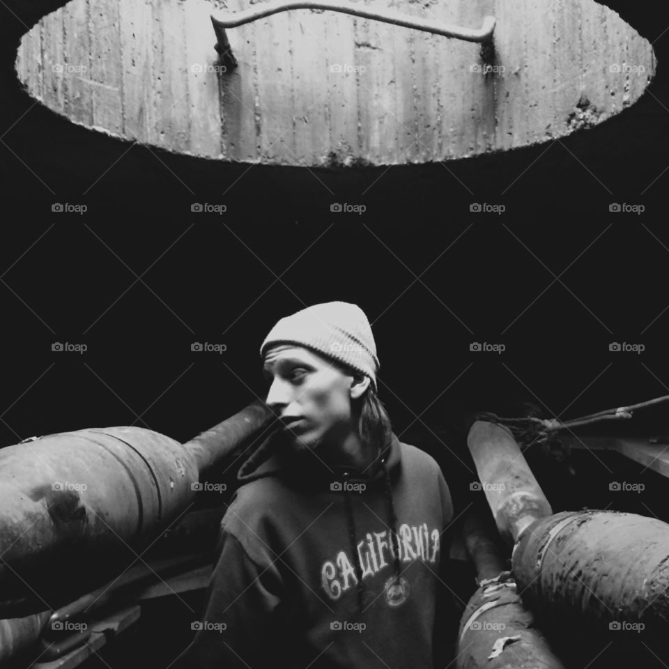 Young man standing inside manhole