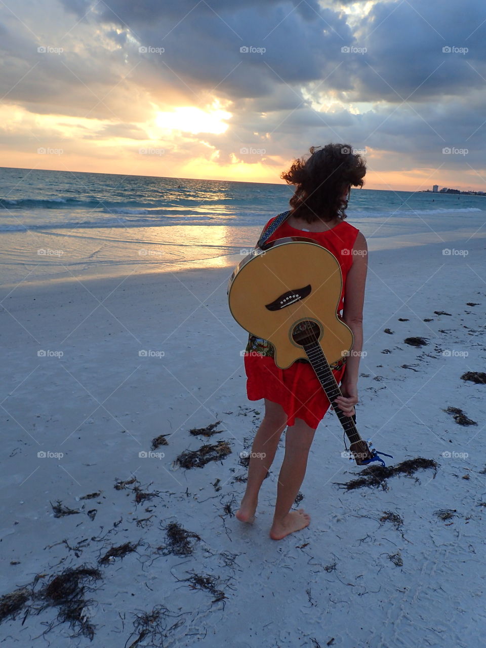 Summer sunset at the beach taking quiet stroll with guitar pondering life