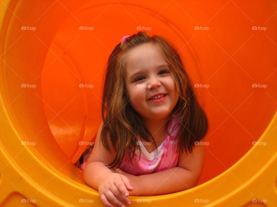 Girl smiles in playground tunnel