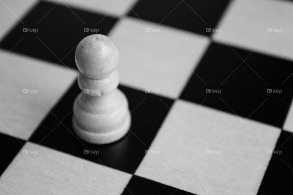 Black and white chess board and a single pawn wood materials macro shot close up