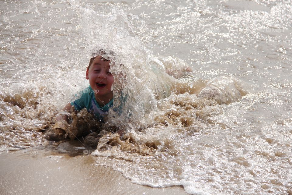 Close-up of a boy playing in wave on beach