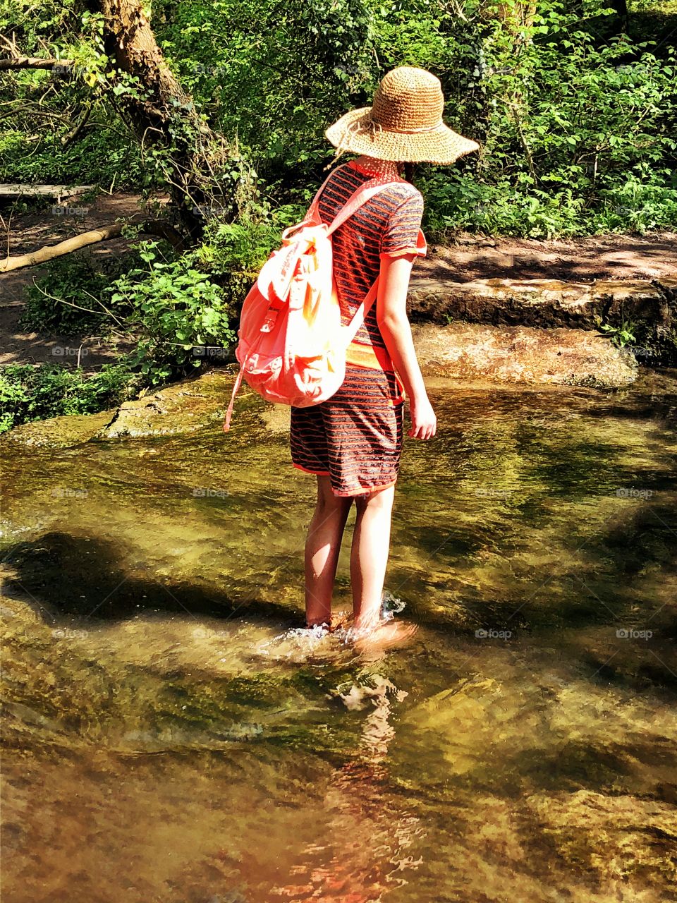 Girl paddling barefoot in the river enjoying the summer sunshine 