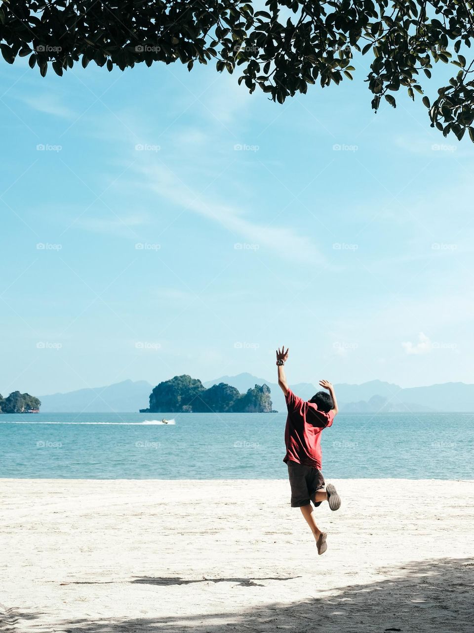 A boy jumping joy on the sandy beach