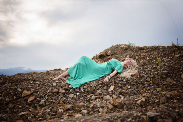 Blonde woman lying on rock stones