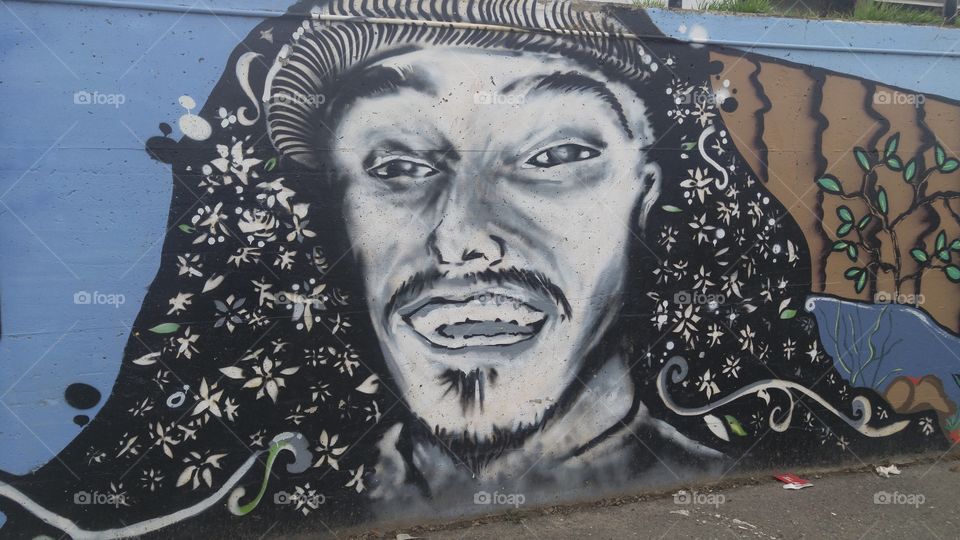 Wall in parkinglot with a portrait of a smiling man with a goatee spray painted onto it
